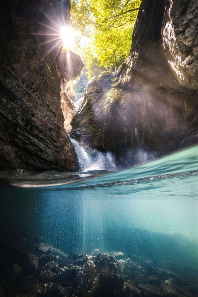Sonnenschein in Bergschlucht mit Wasserfall.