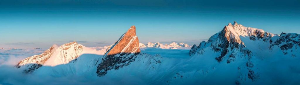 Morgenlicht auf verschneiter Bergkette.