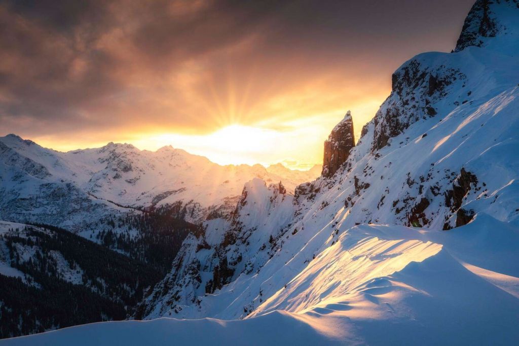 Abendsonne hinter verschneiten Berggipfeln