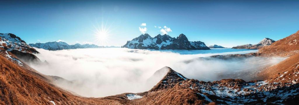Sonnendurchflutetes Bergtal mit Wolkenmeer.