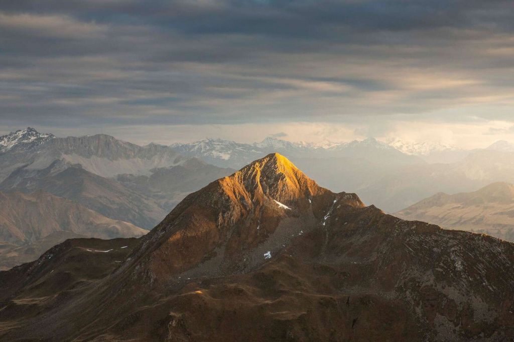 Goldenes Sonnenlicht auf Bergspitze bei Sonnenaufgang.