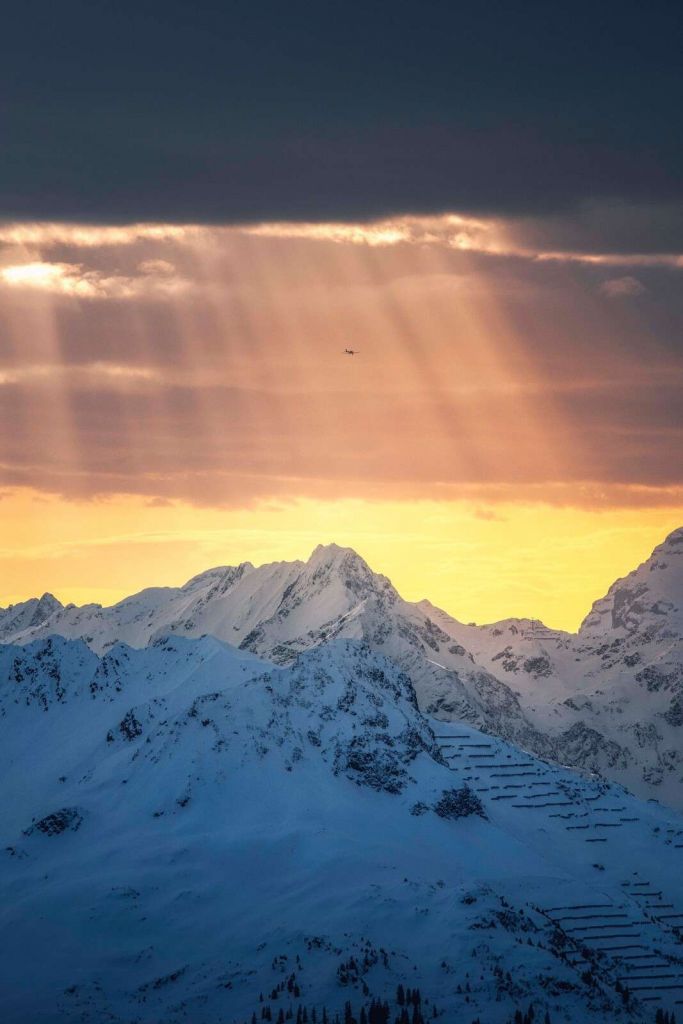 Sonnestrahlen über verschneiten Berggipfeln