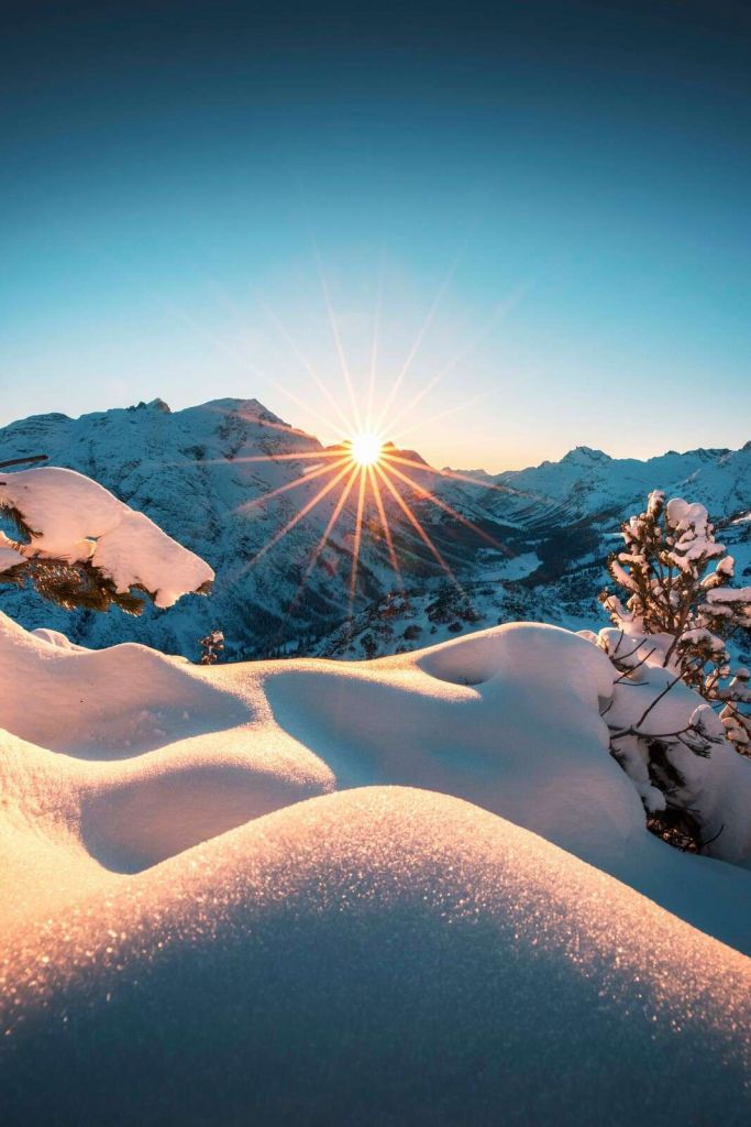 Morgensonne über verschneitem Tal.