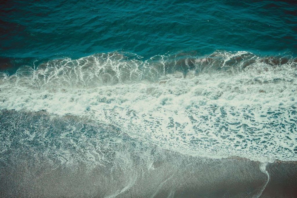 Schaumige Wellen auf nassem Sand