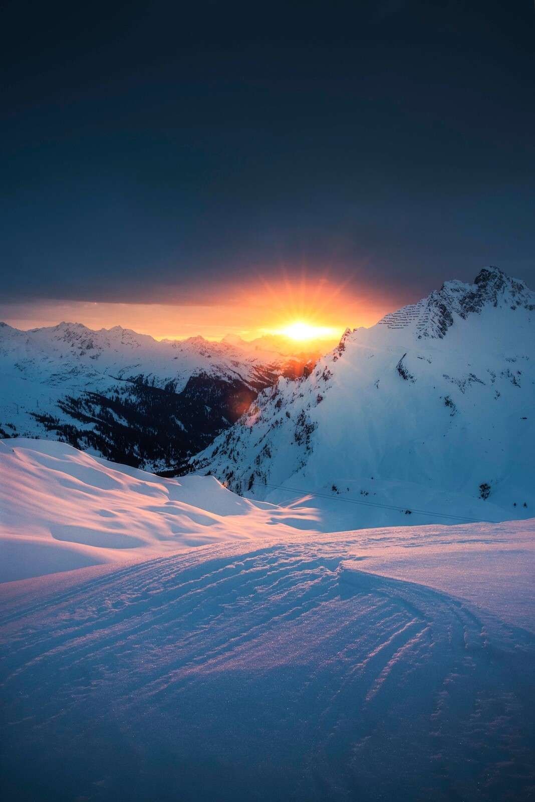 Untergehende Sonne über verschneiten Alpengipfeln.