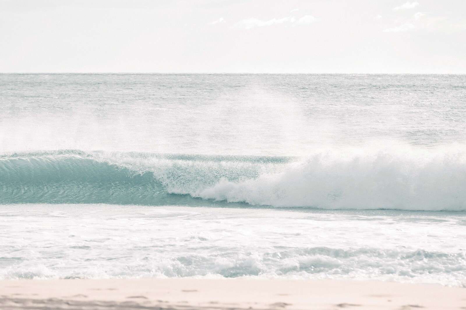 Brechende Welle am klaren Strand