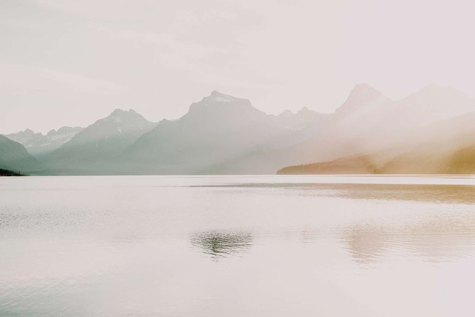 Nebelige Berge über ruhigem See.